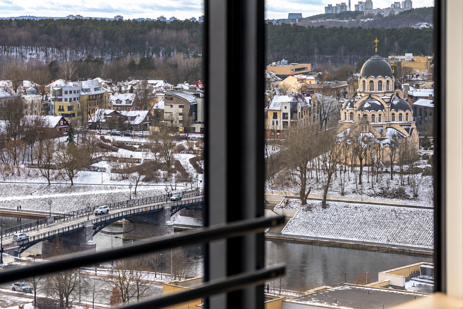 A snow-covered riverbank, a bridge and a church can be seen through the window.
