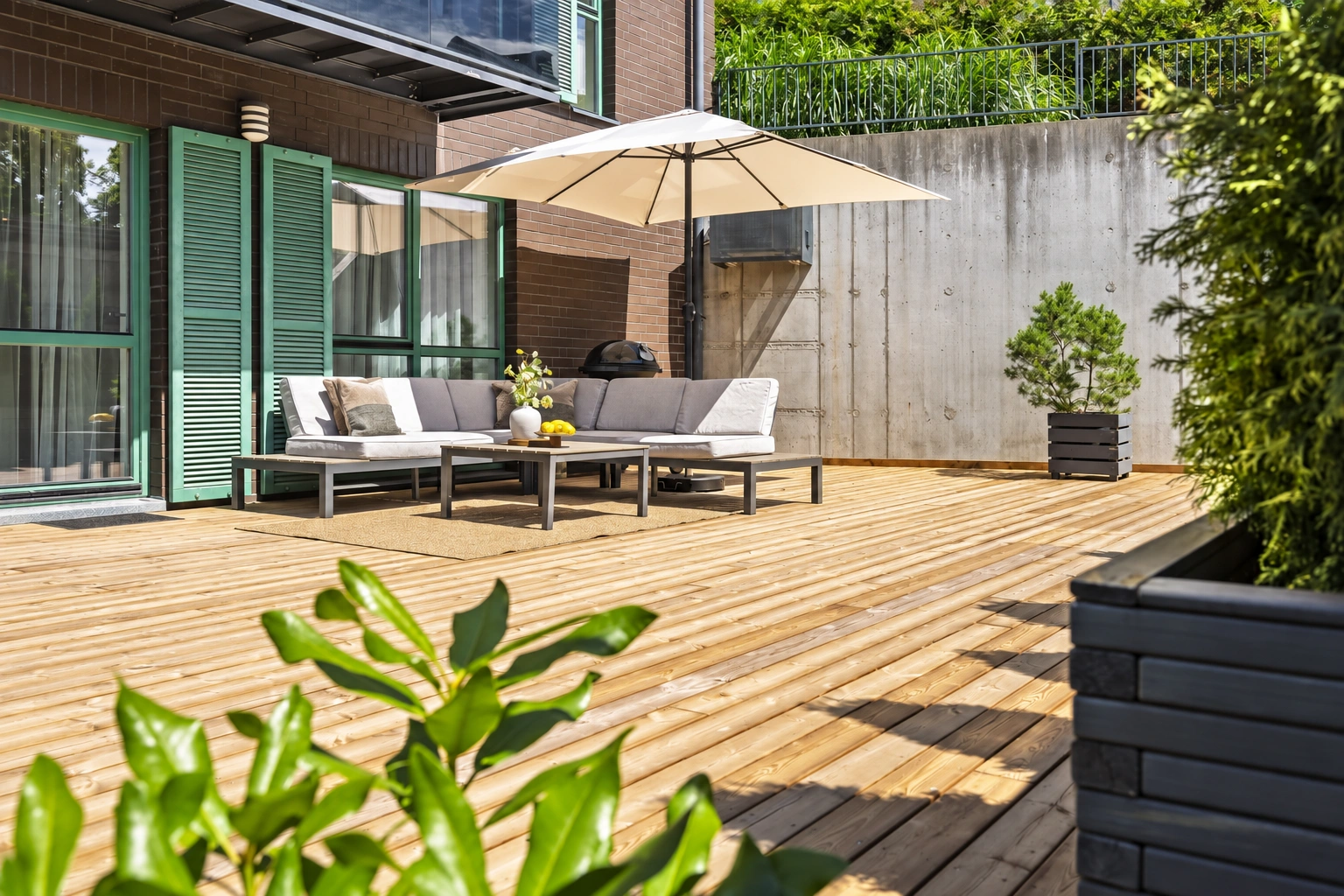 Eine Terrasse mit Gartenmöbeln und einem darüber aufgespannten Schirm.