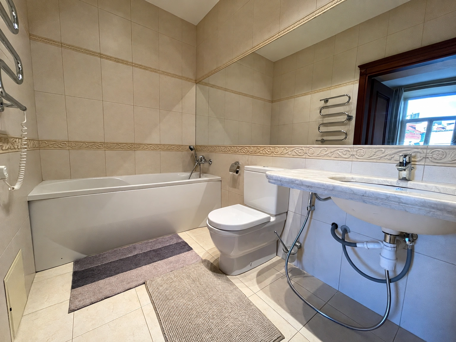 Badezimmer mit einer Badewanne und einem breiten Spiegel über dem Waschbecken.