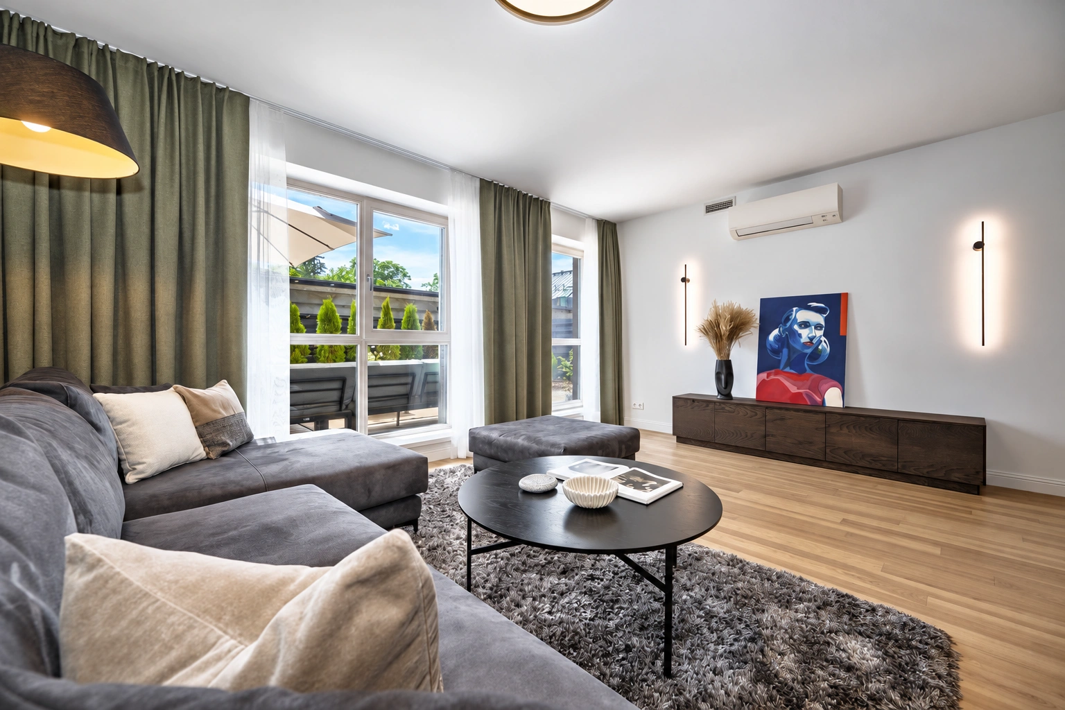 Wohnzimmer mit einem grauen Ecksofa und einem runden Couchtisch.