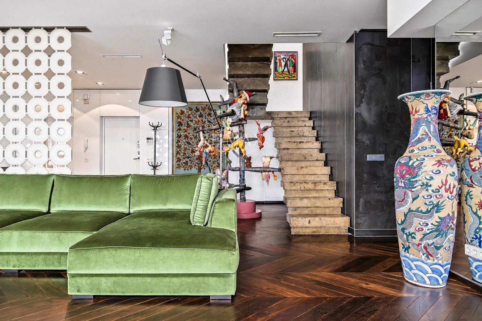 Im Wohnzimmer steht ein grünes Ecksofa, und dahinter ist eine Treppe zu sehen.