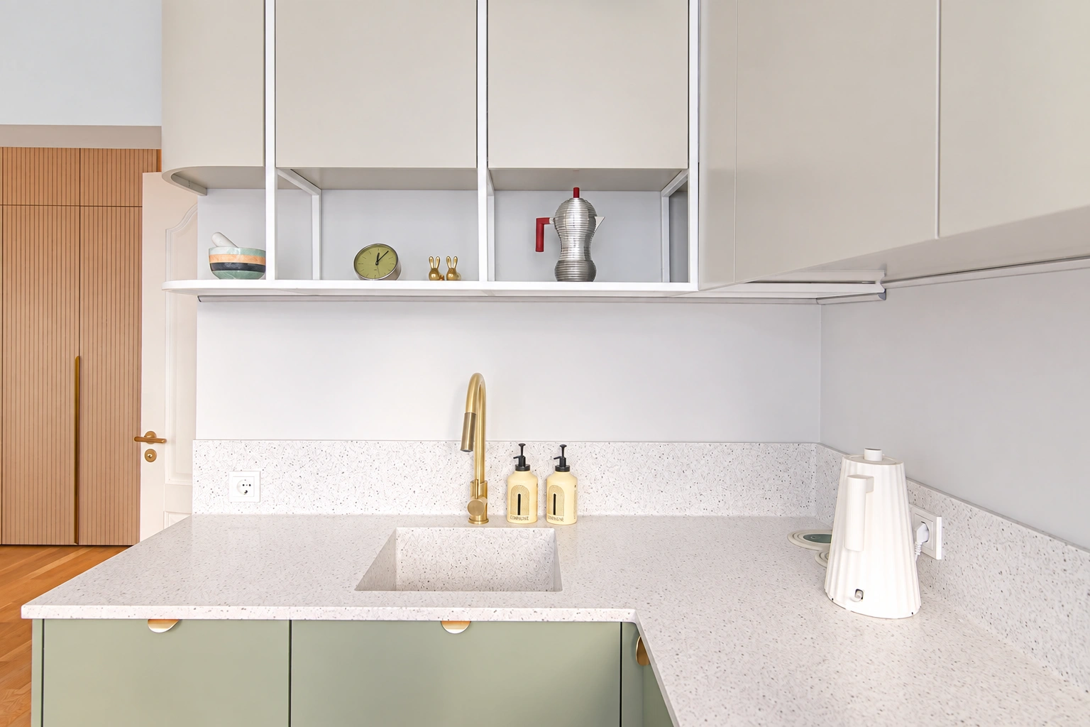 Kitchen with light-colored wall cabinets and a sink with a gold-colored faucet.