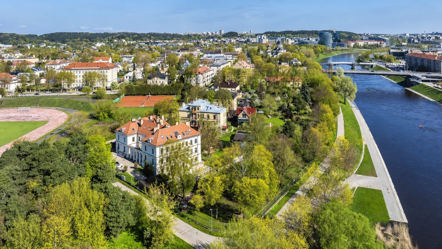 Buildings among trees, a river, and a path running along the bank are visible from above.