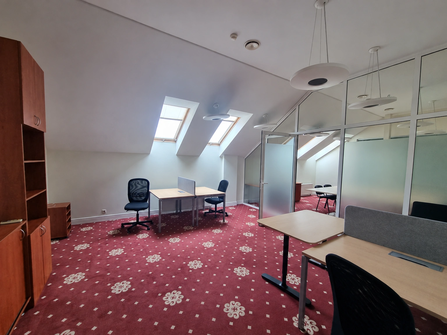 Tables and chairs stand in a room beneath sloping ceilings with skylights.