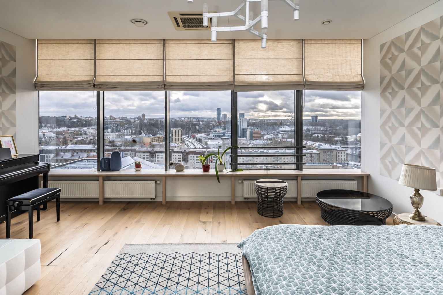 Living room with a piano and wide windows through which city buildings are visible.