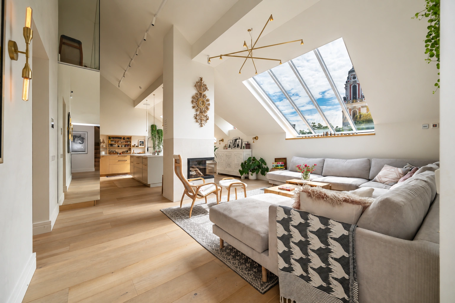 Wohnzimmer mit einem grauen Ecksofa und großen Dachfenstern.