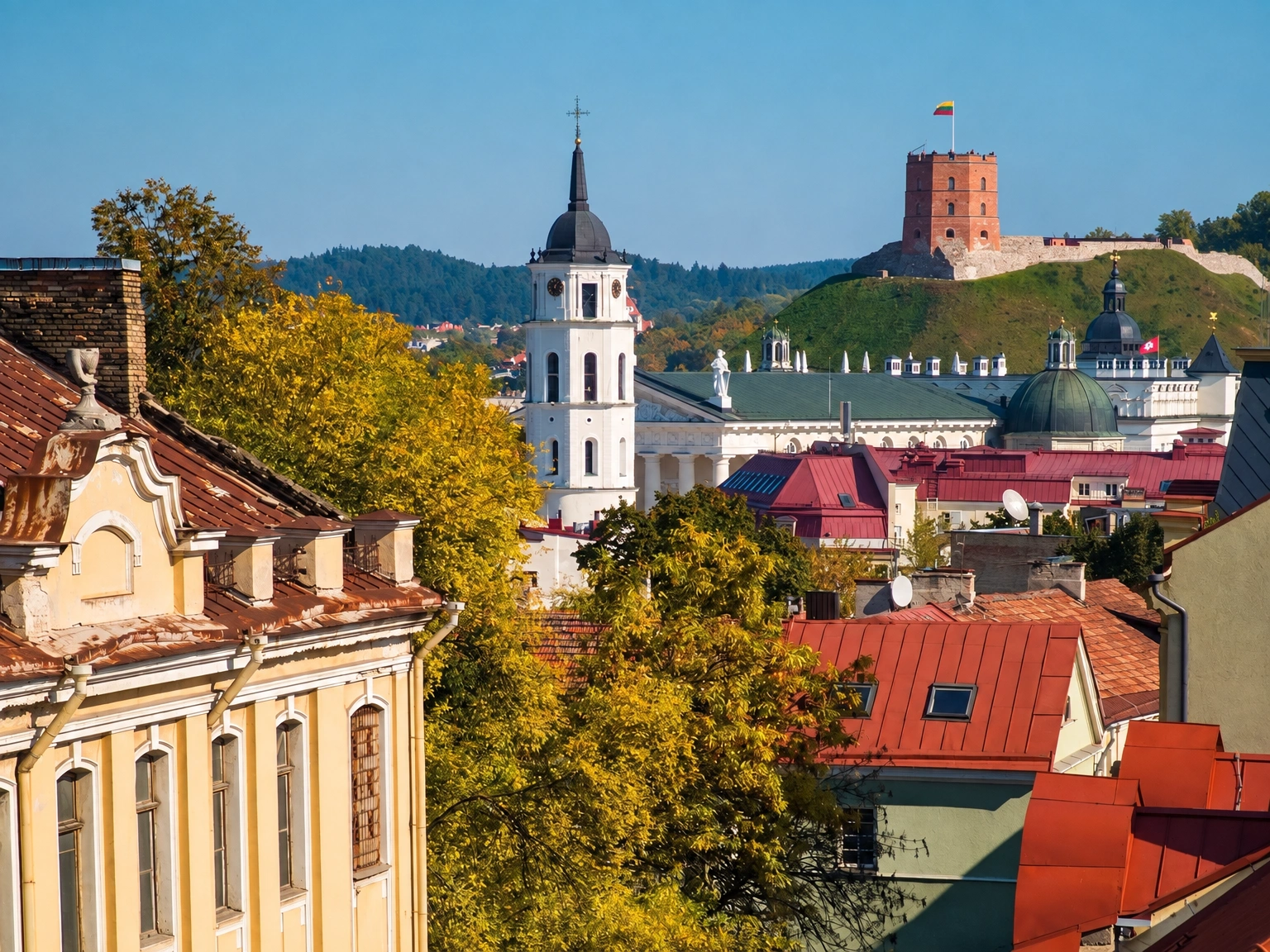 City panorama with red rooftops and a tower on a hill.