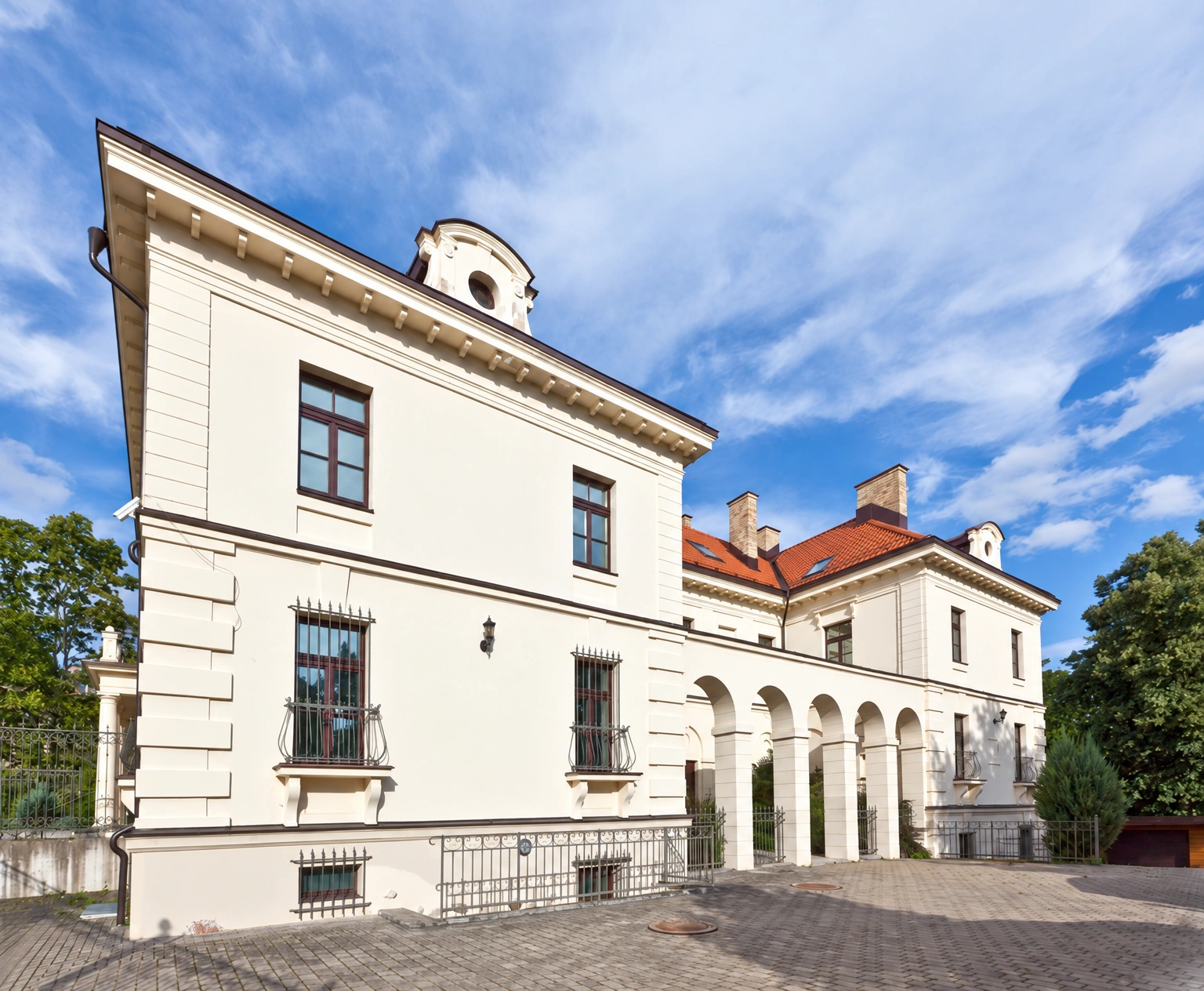 A two-storey building with a red roof and arched openings near the entrance.