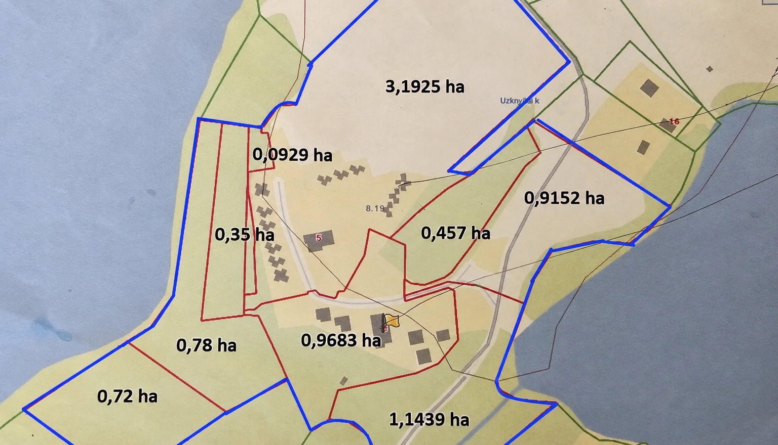 Ein Plan der Grundstücke mit blauen Grenzen und in Hektar angegebenen Flächen.