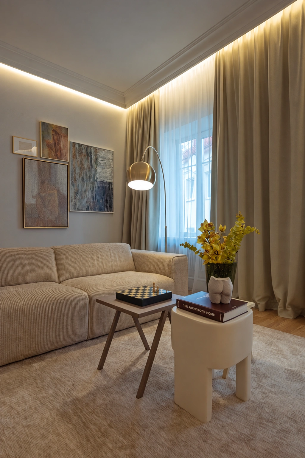 Living room with a light-colored sofa and long curtains covering a large window.