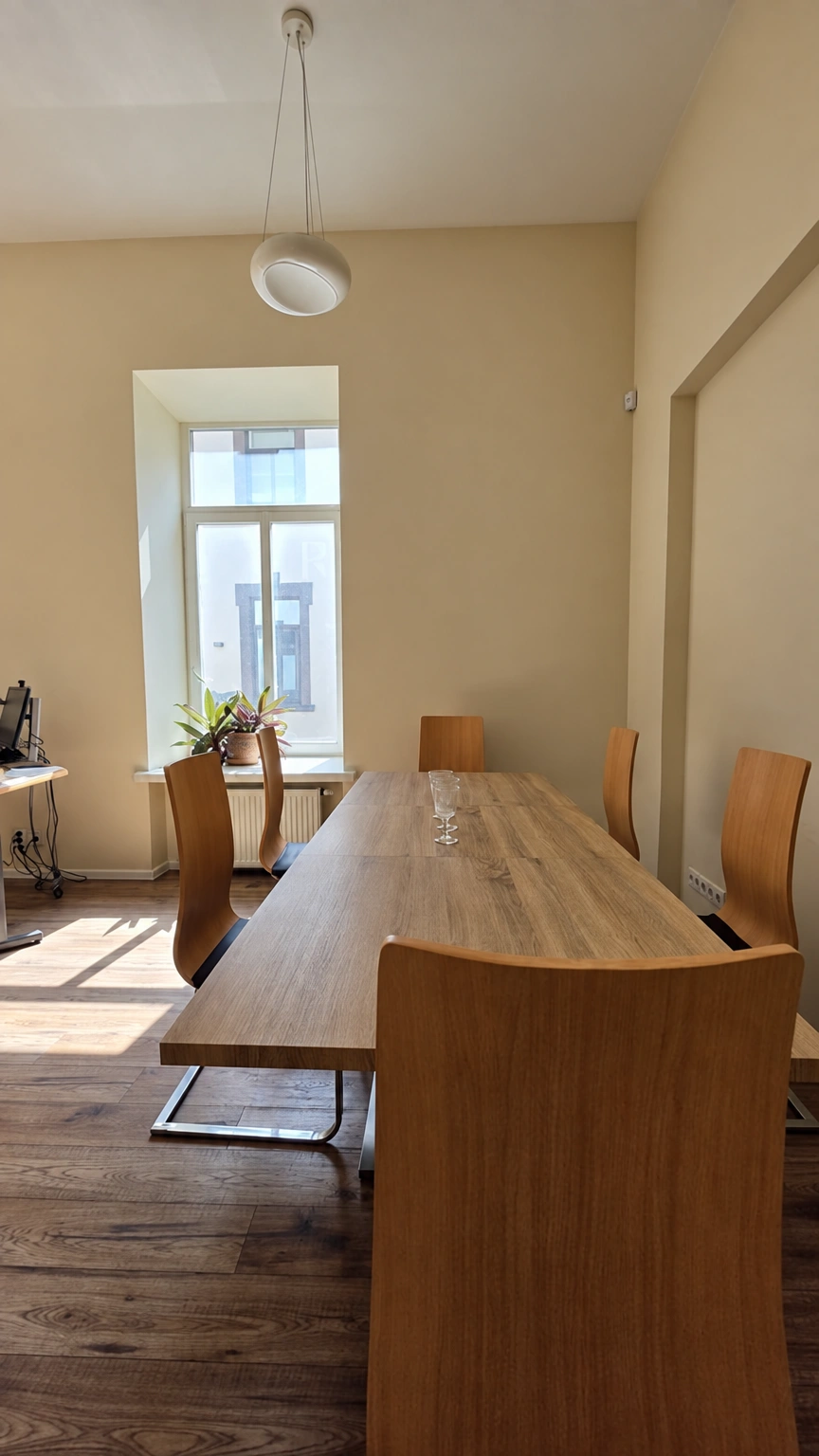 There is a long table with chairs in the room, and potted plants on the windowsill.