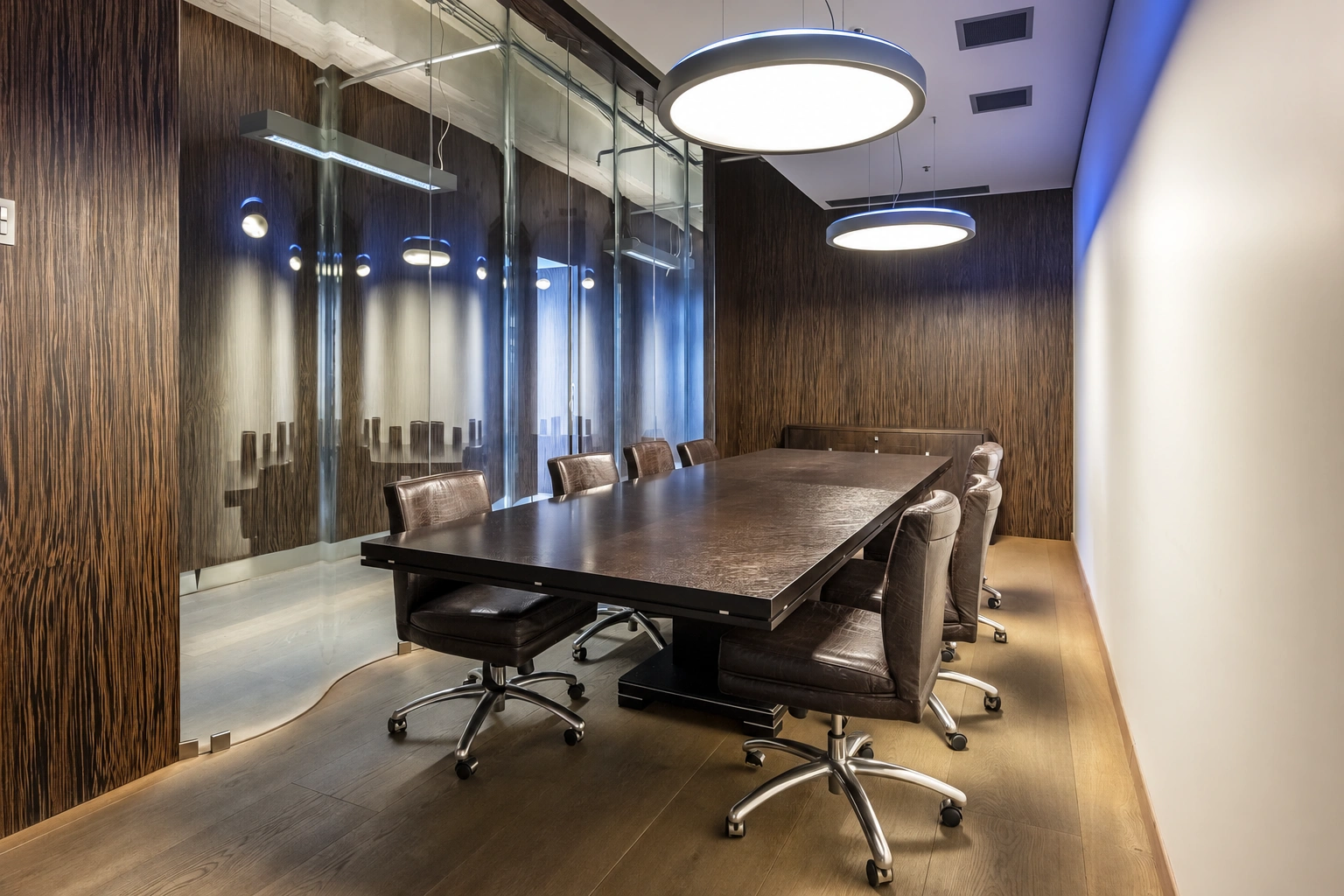 Meeting room with a long table, chairs on casters, and a glass partition.