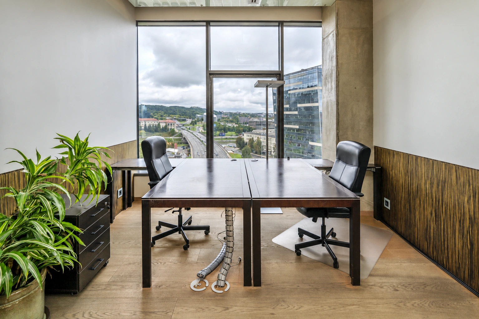 A desk and two office chairs stand by the large windows.