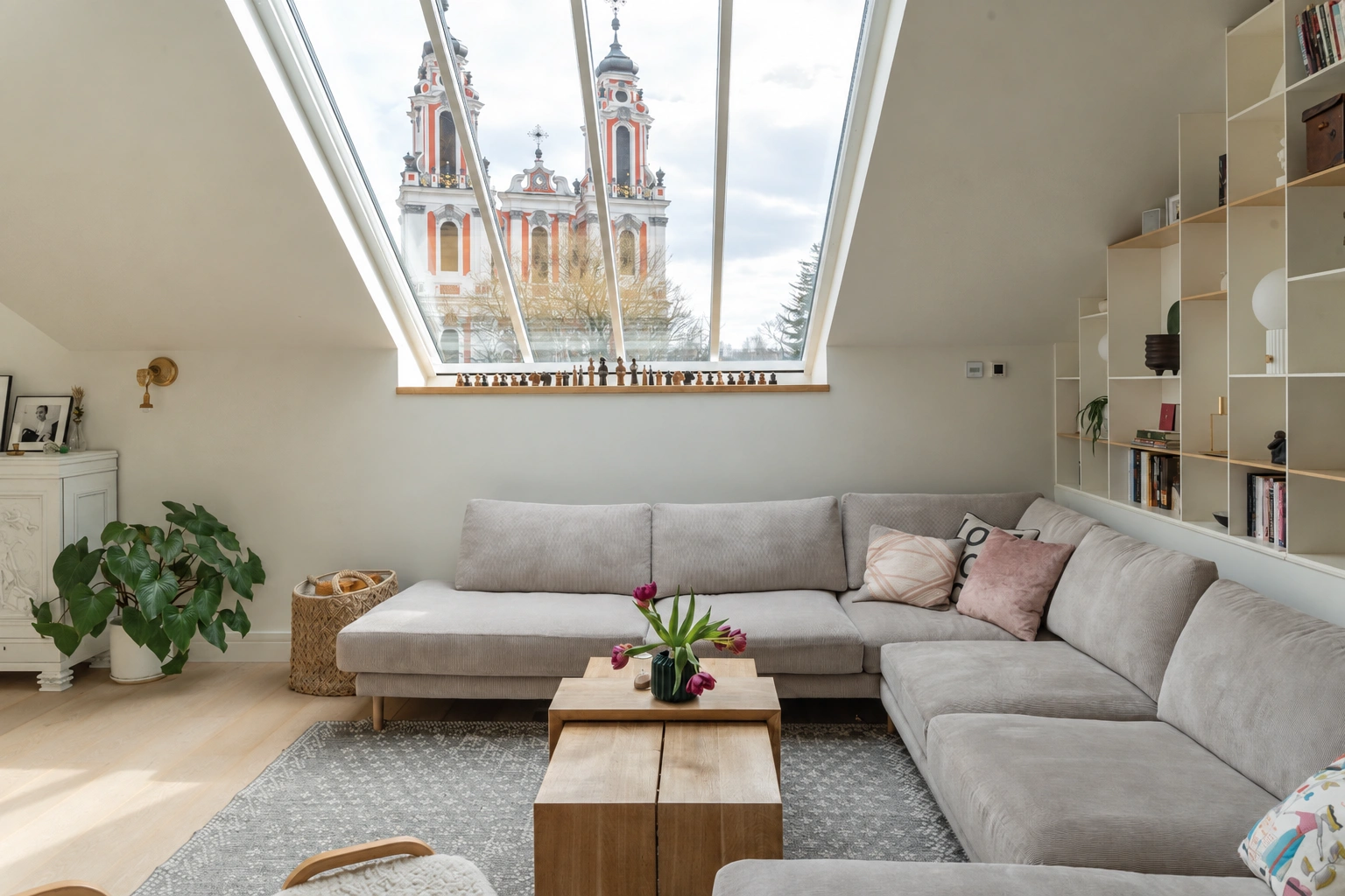 Wohnzimmer mit einem Ecksofa und einem großen Dachfenster in der schrägen Decke.