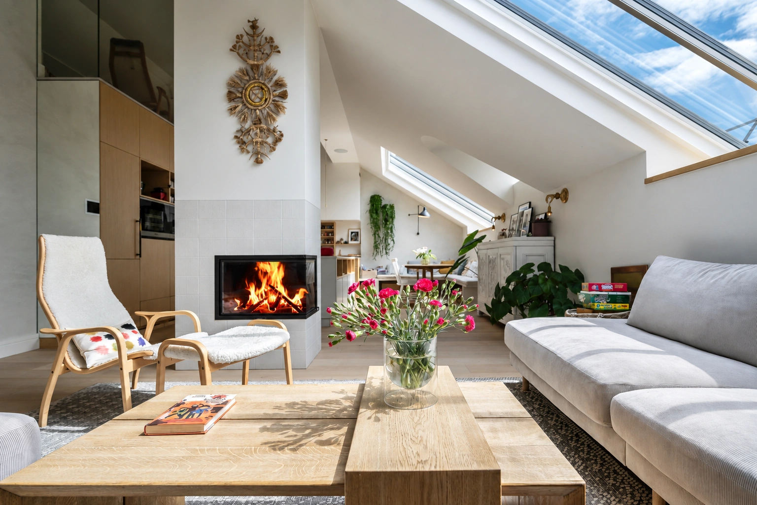 Wohnzimmer mit einem Feuer im Kamin und großen Dachfenstern in der schrägen Decke.