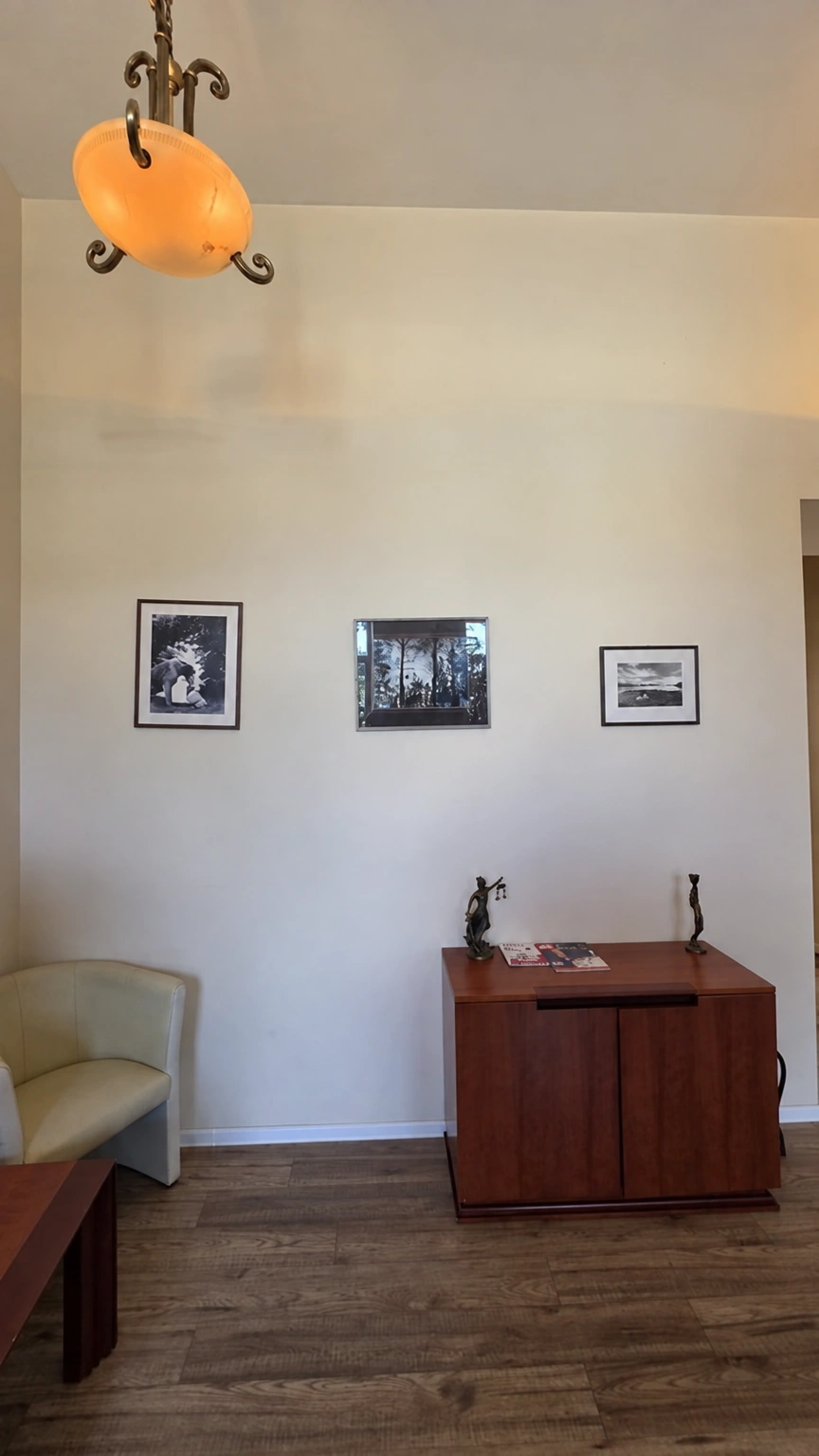 There is a small cabinet and an armchair in the room, and three framed pictures hang on the wall.