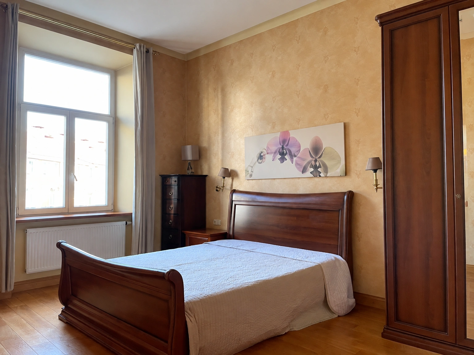 Ein Schlafzimmer mit einem Doppelbett und einem großen Fenster, neben dem Vorhänge hängen.