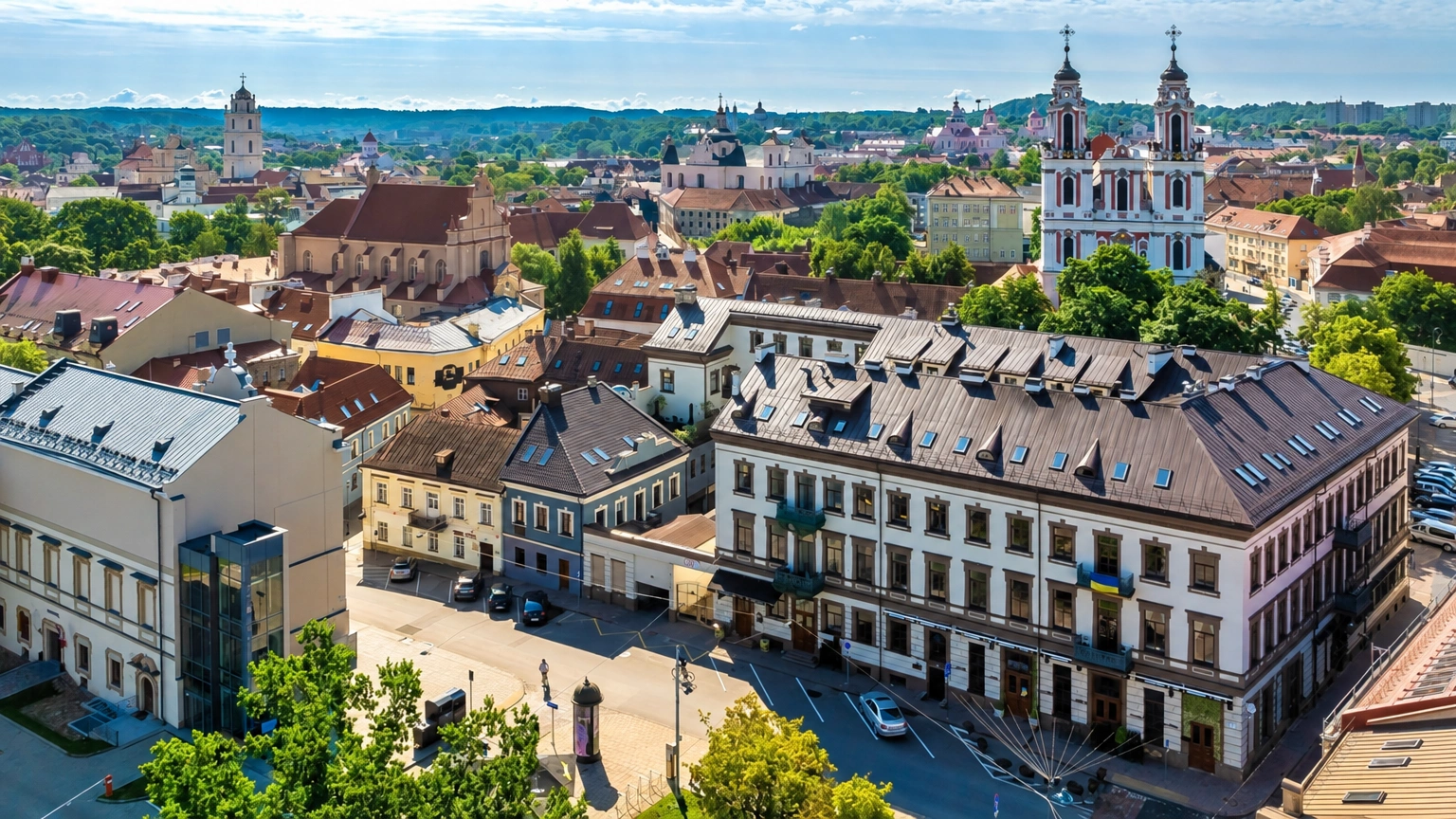 City panorama with multi-storey buildings and church towers rising above the rooftops.