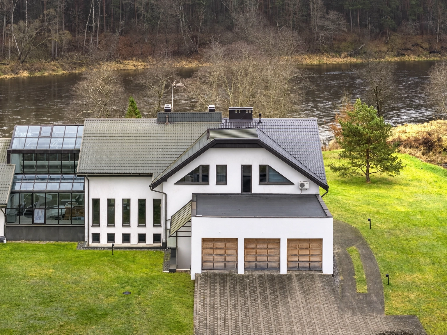 Ein Haus mit drei Garagentoren steht neben einem Gewässer.