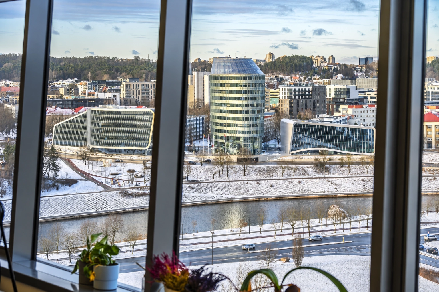 Through the large windows, a river, a snow-covered embankment and city buildings are visible.
