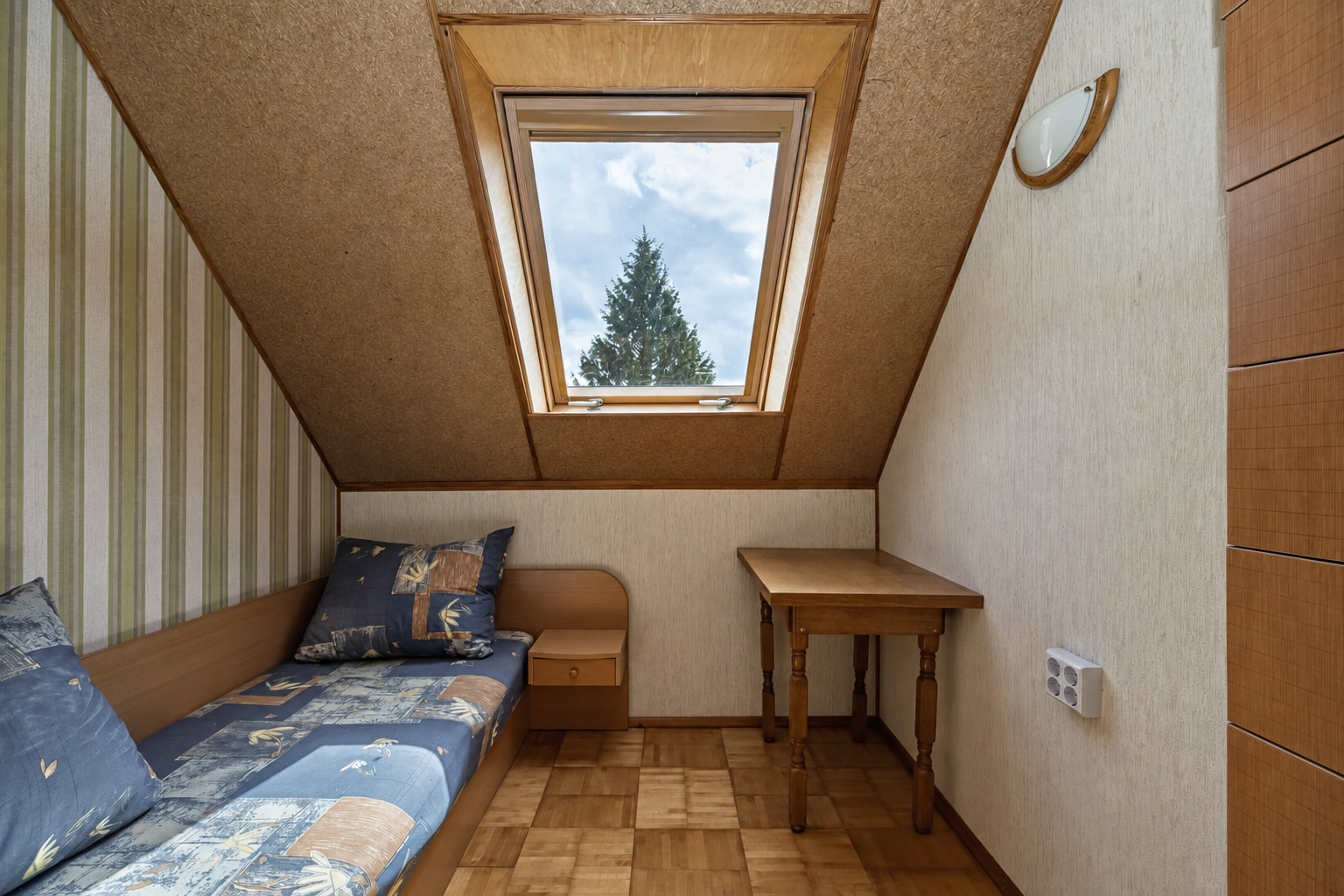 An attic room with a skylight and a sofa placed along the wall.