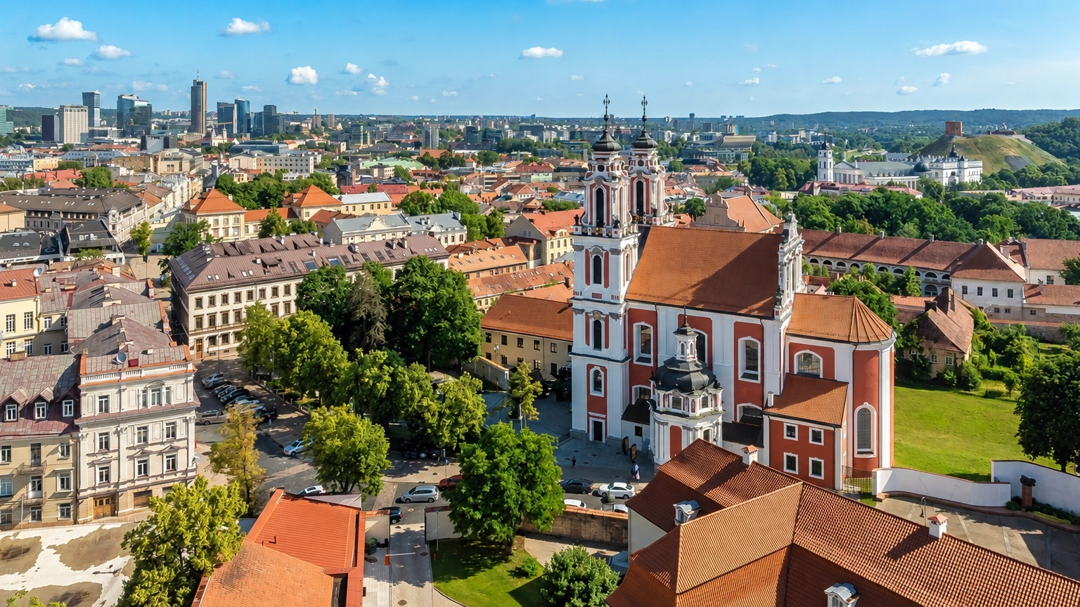 City panorama with church towers and the red roofs of surrounding buildings.