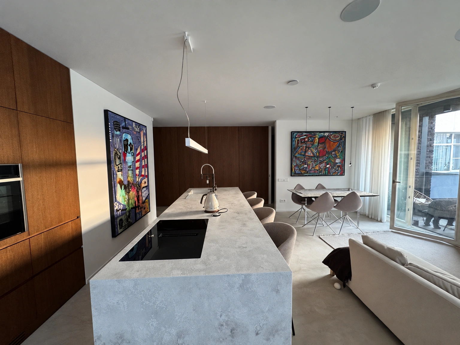 Combined kitchen and living room area with an island and large windows.