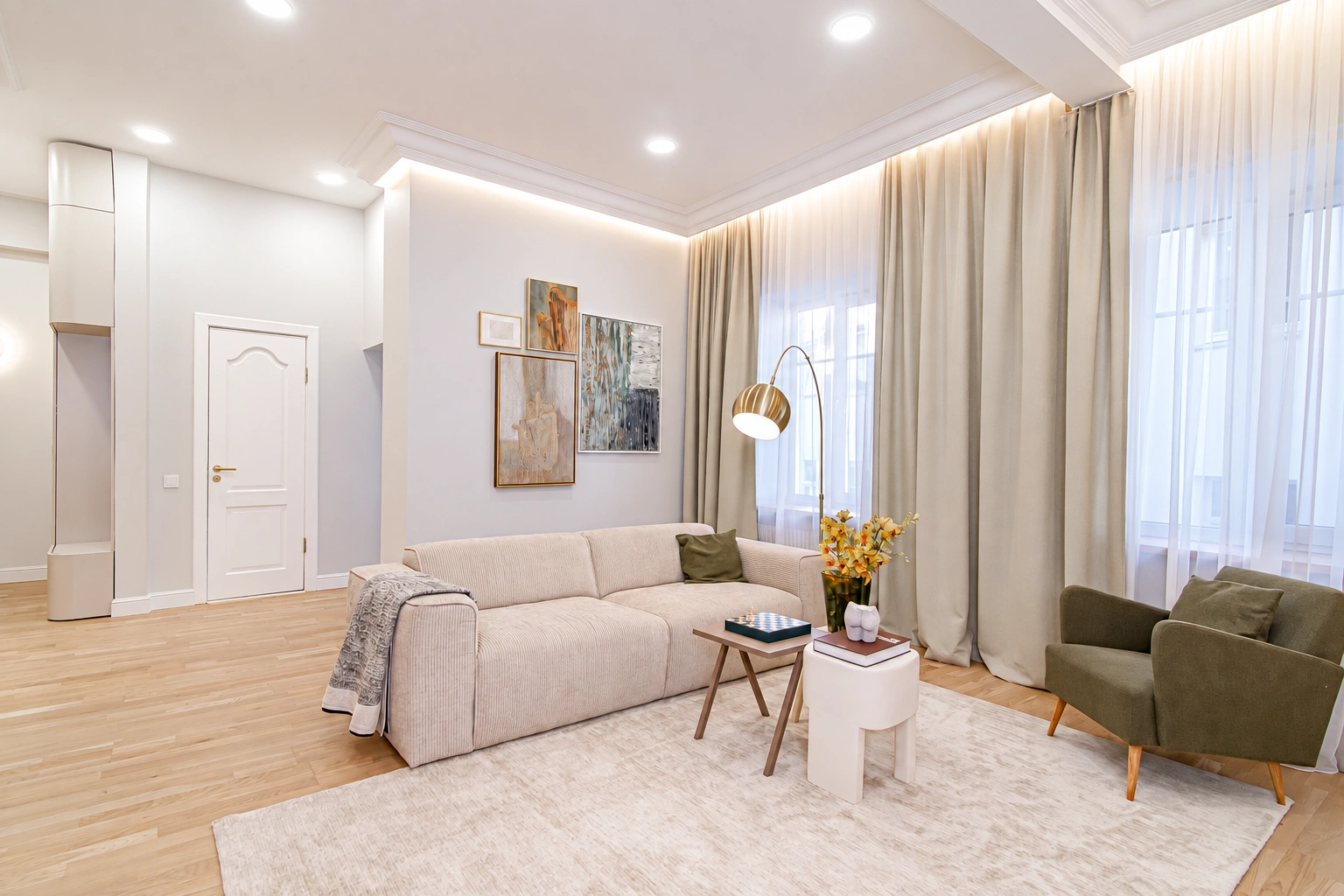 There is a light-colored sofa and a green armchair in the living room, and curtains cover the large windows.