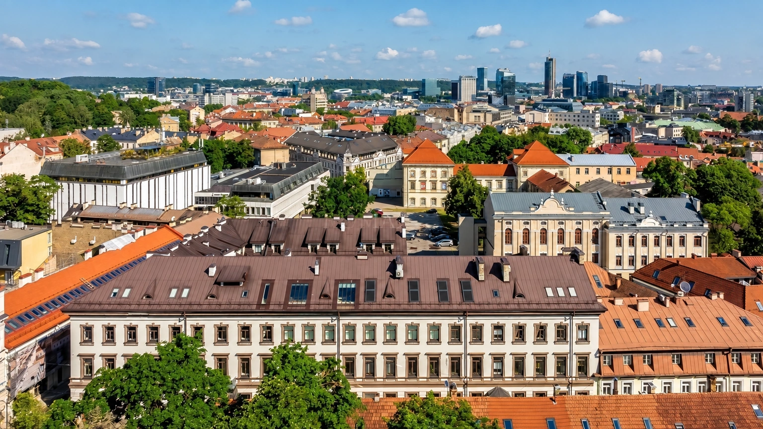 City panorama with red roofs and high-rise buildings visible in the distance.