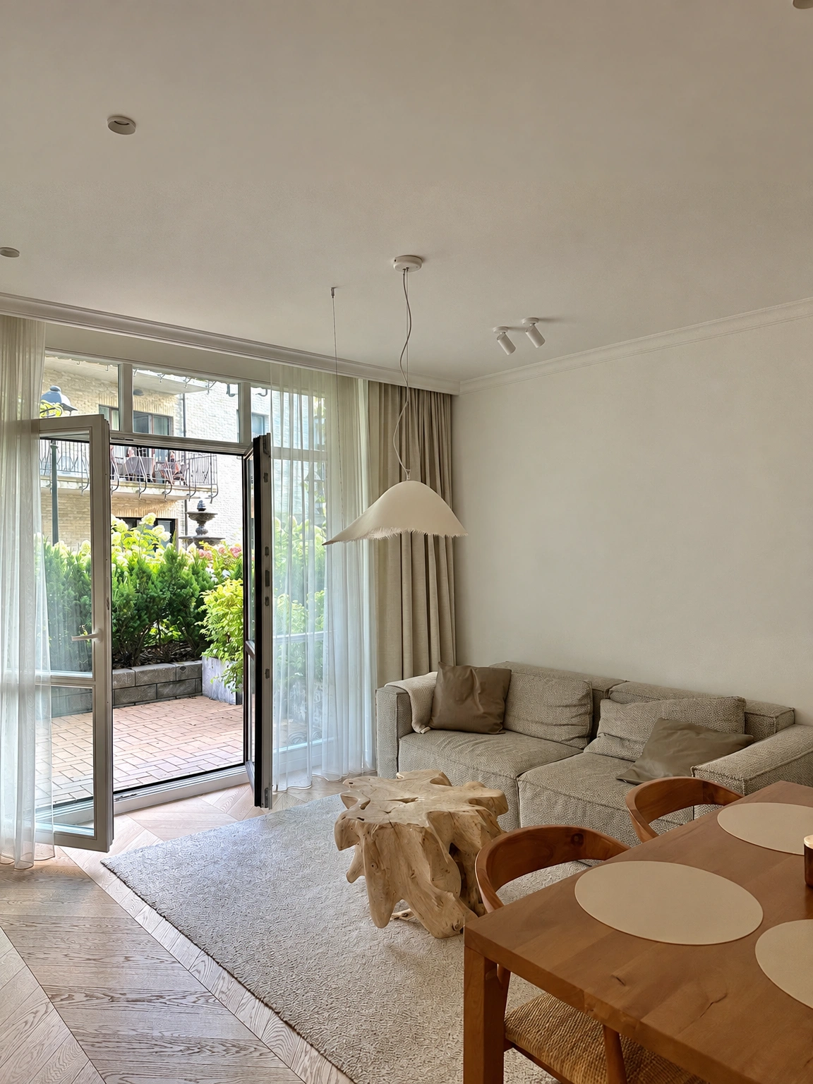 Wohnzimmer mit einem Ecksofa und offenen Türen zur Terrasse.