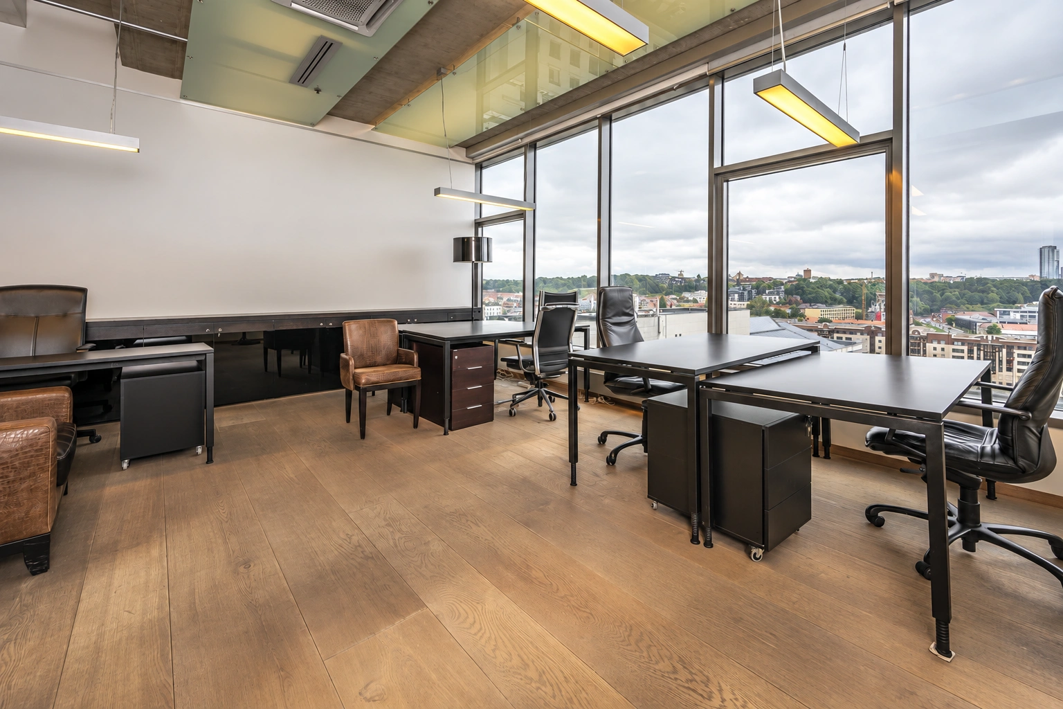 Office space with desks and large windows through which the city can be seen.