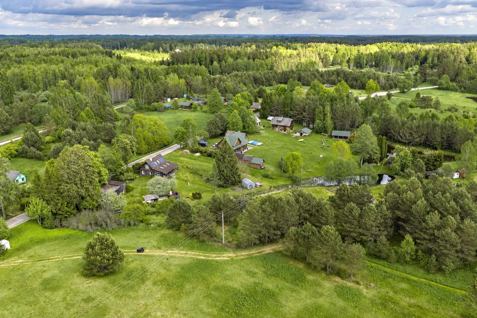 Houses seen from above among green meadows and trees.