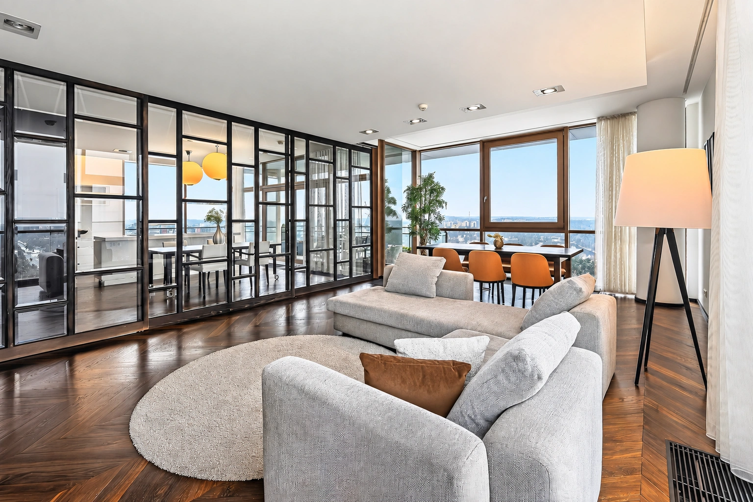 Wohnzimmer mit zwei grauen Sofas, großen Fenstern und einer Glastrennwand.