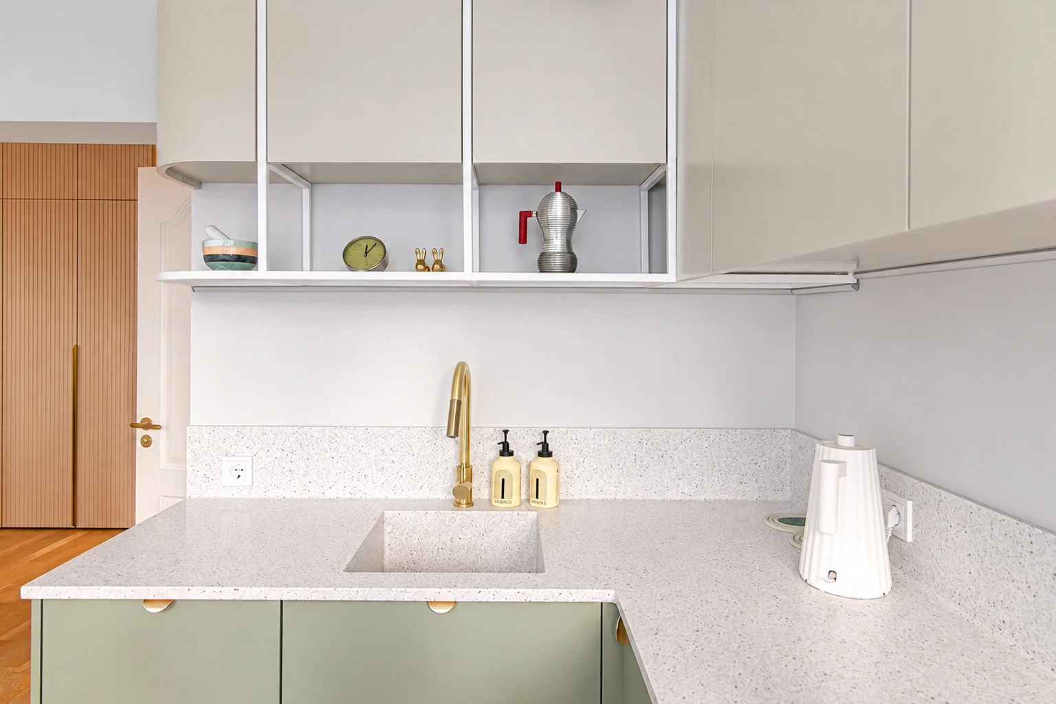 White cabinets and a sink with a tall gold-colored mixer tap can be seen in the kitchen.