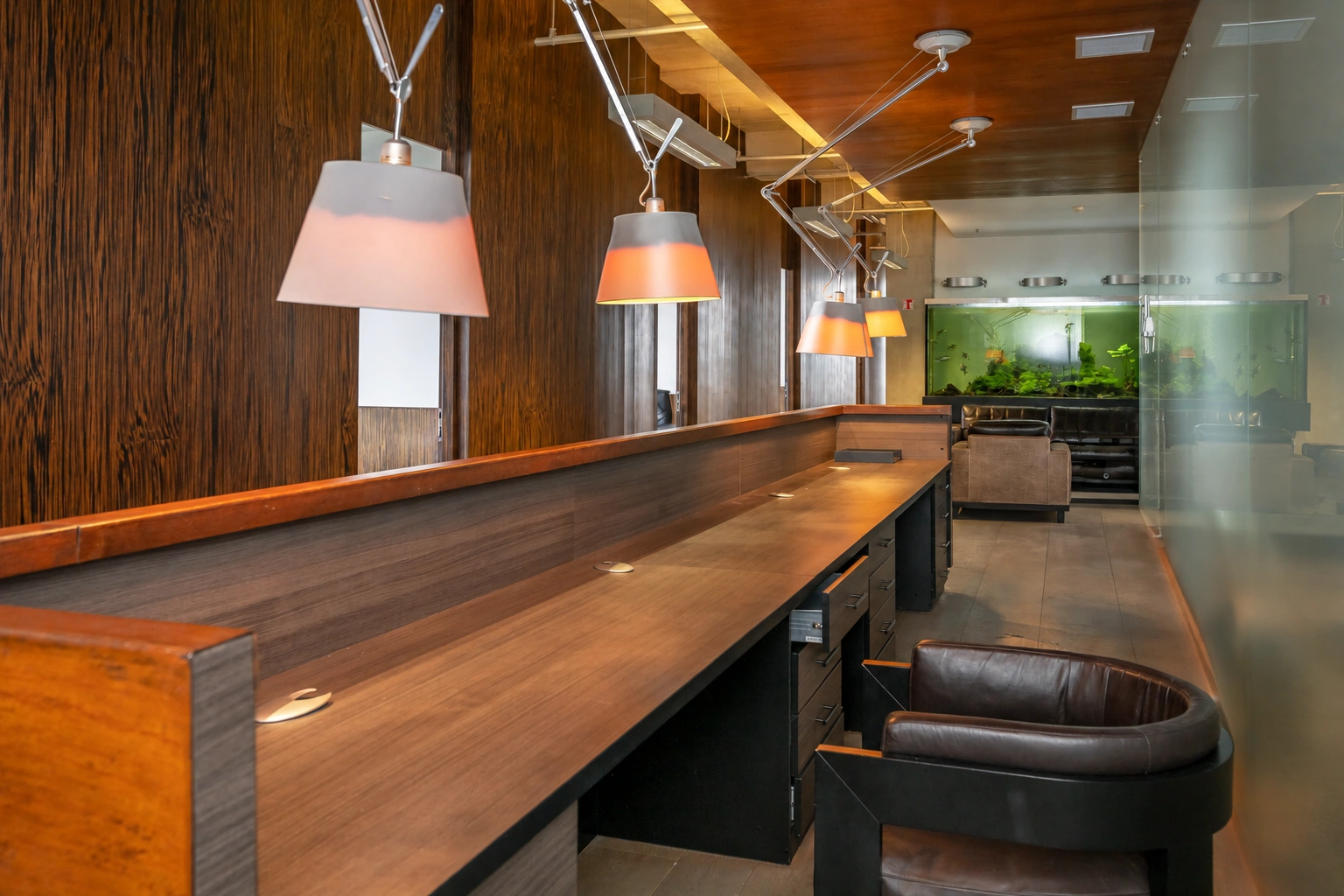 A long countertop with light fixtures hanging above it and a dark armchair beside it.