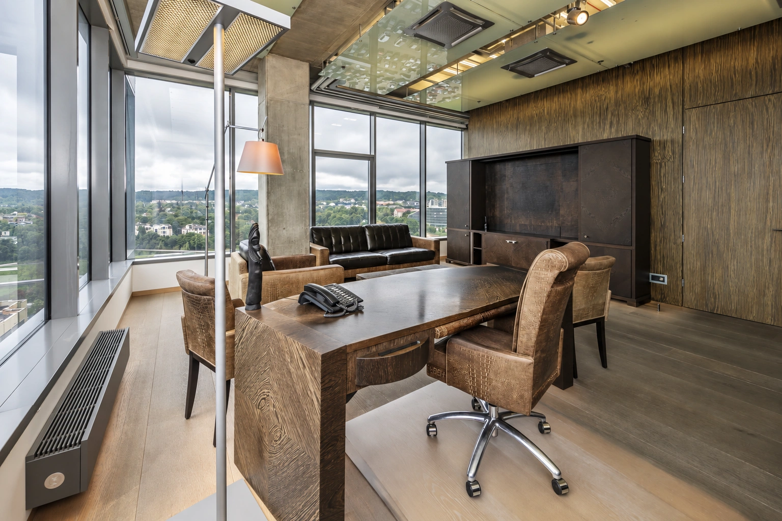 Study with a desk, upholstered chairs and large windows.