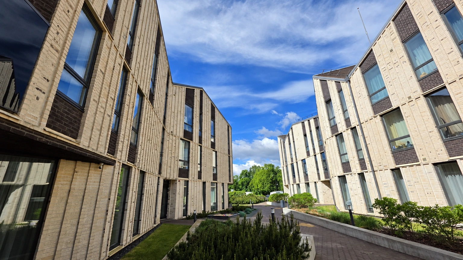 A path runs through the courtyard of the apartment buildings, with shrubs growing along it.