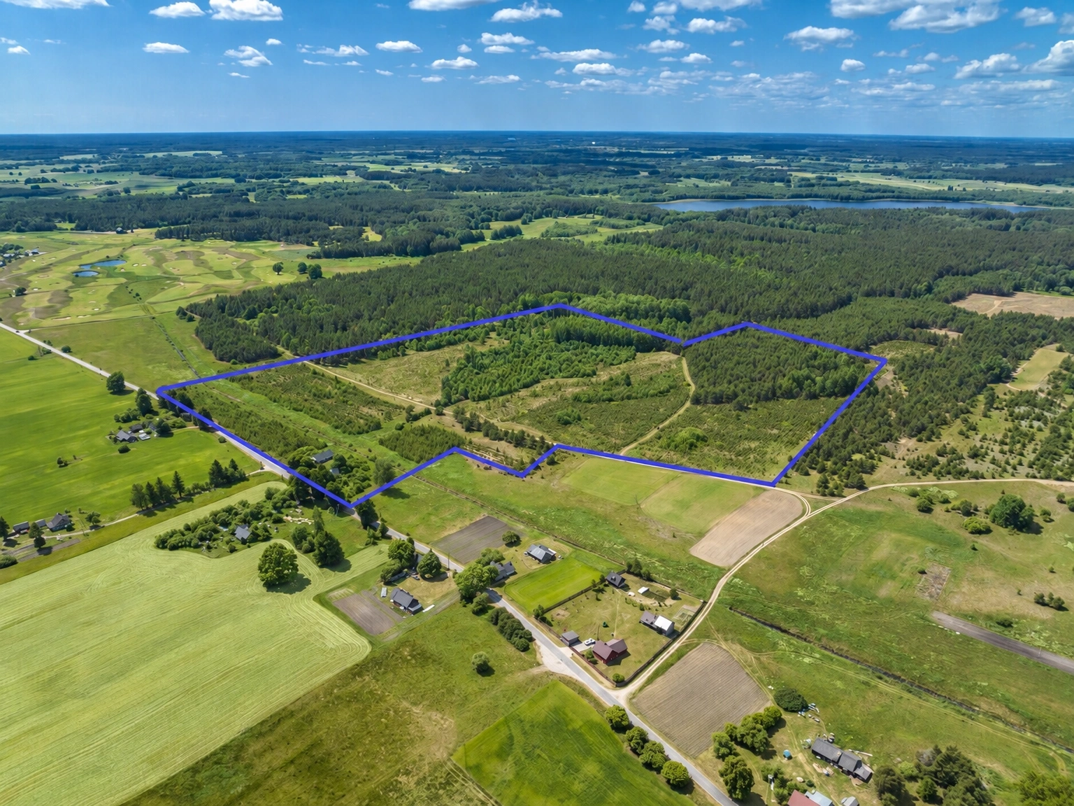 Von oben ist ein mit einer blauen Linie markiertes Gebiet mit Feldern und Wald zu sehen.