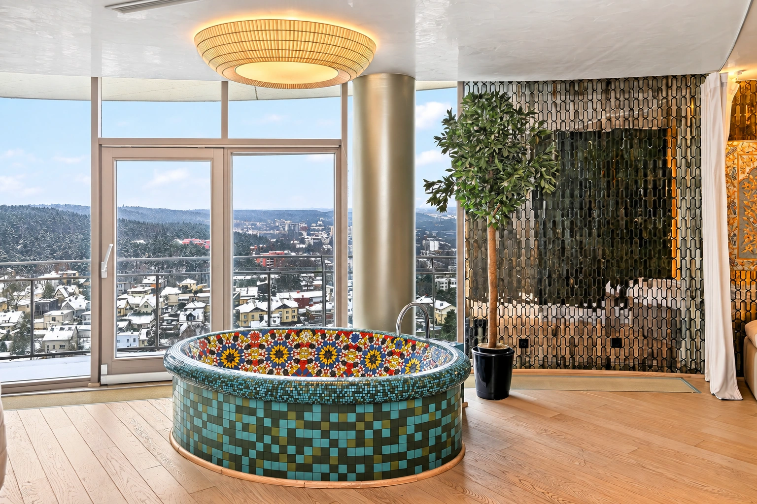 Eine runde Badewanne mit farbenfroher Mosaikverkleidung bei großen Fenstern, daneben eine Topfpflanze.