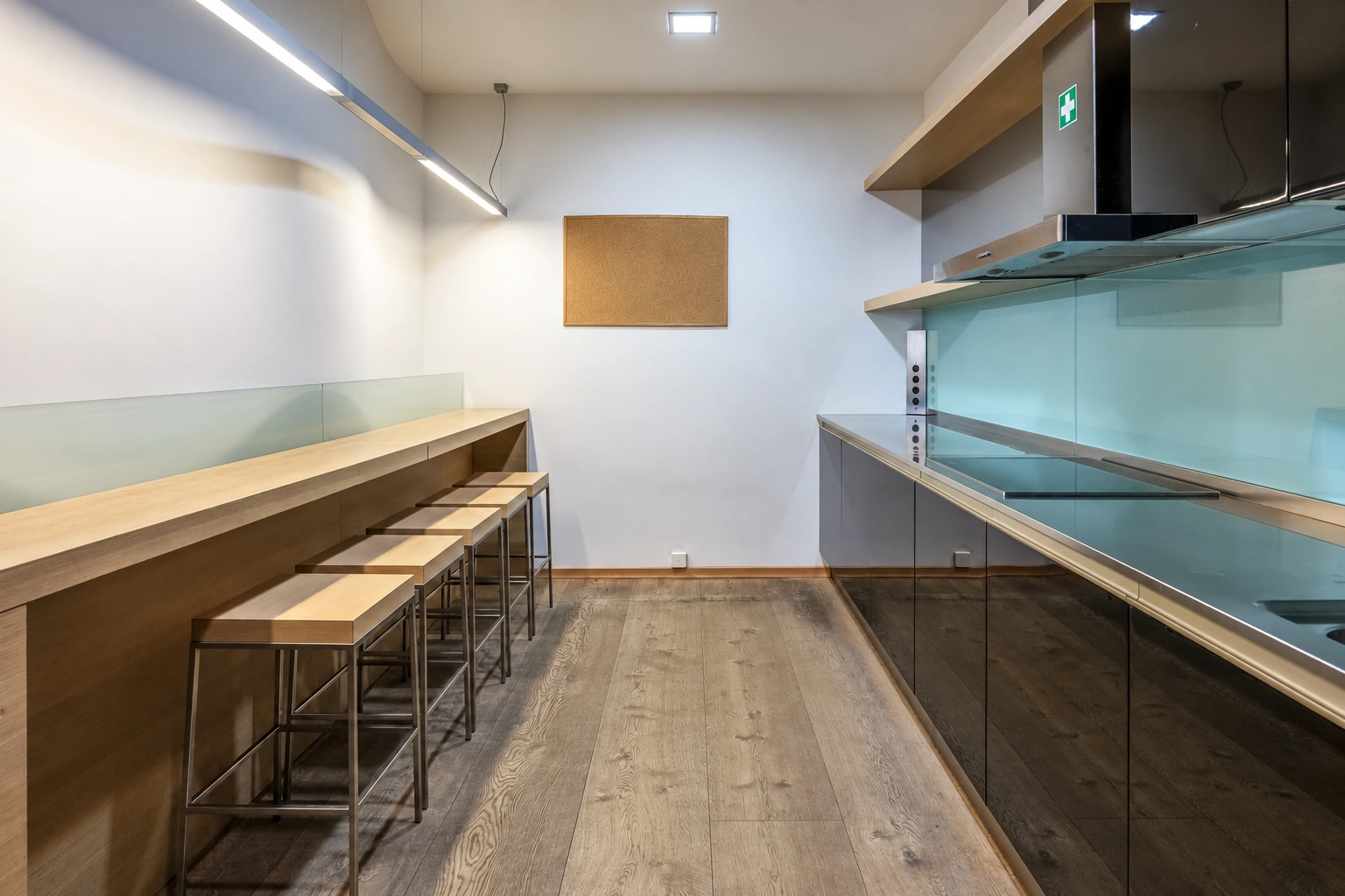 A narrow kitchen with dark cabinets and bar stools at a long countertop.