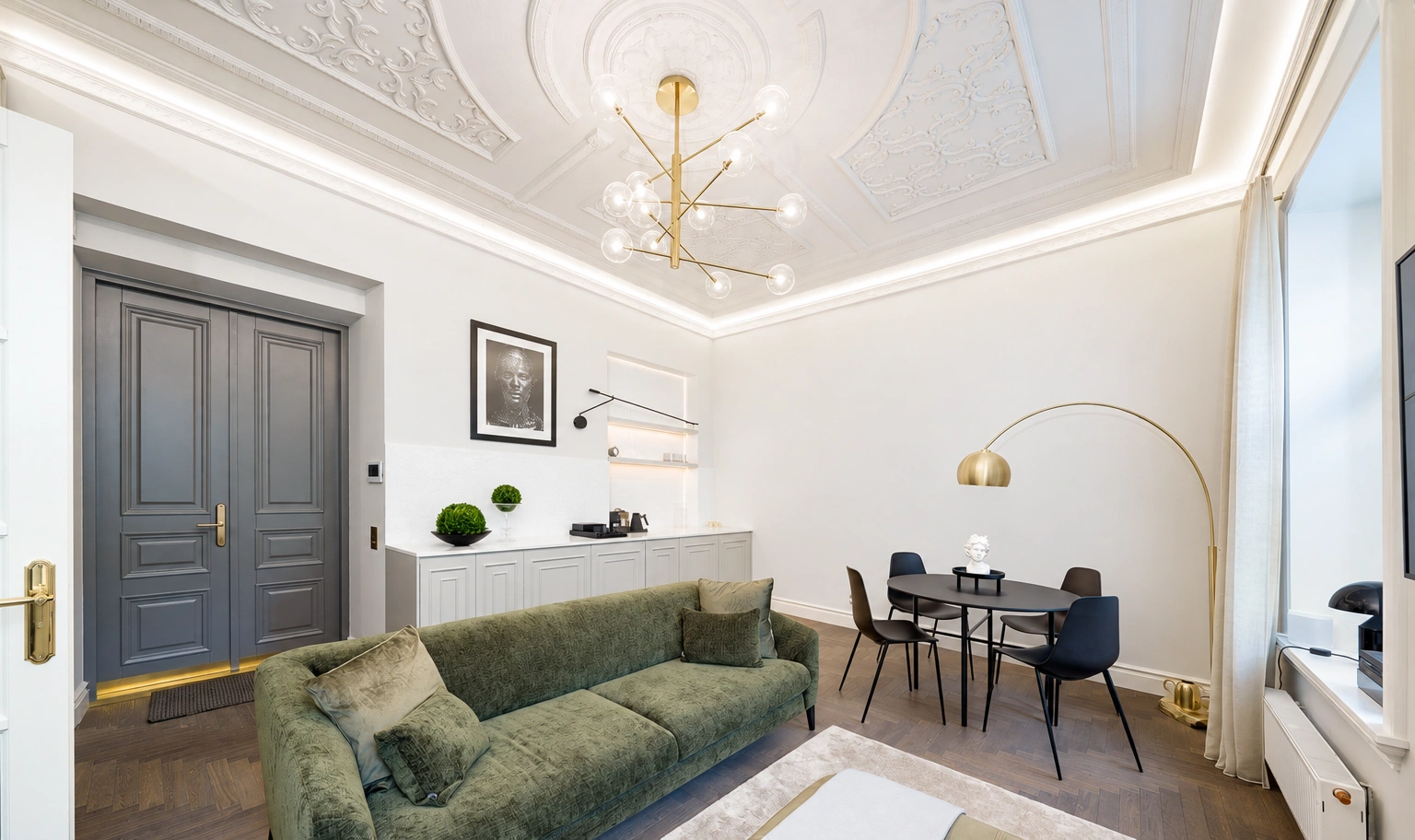 Svetainė su žalia sofa ir nedideliu stalu prie lango.