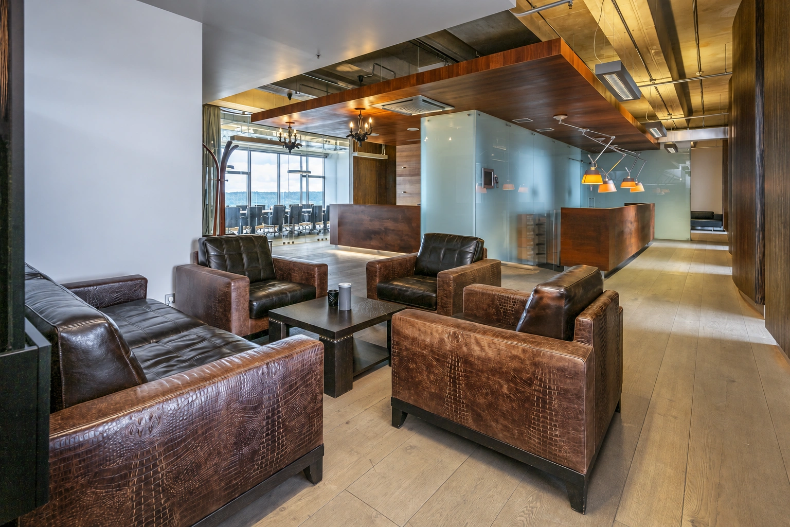 Armchairs and low tables are arranged in the lounge area, and exposed structural elements are visible on the ceiling.