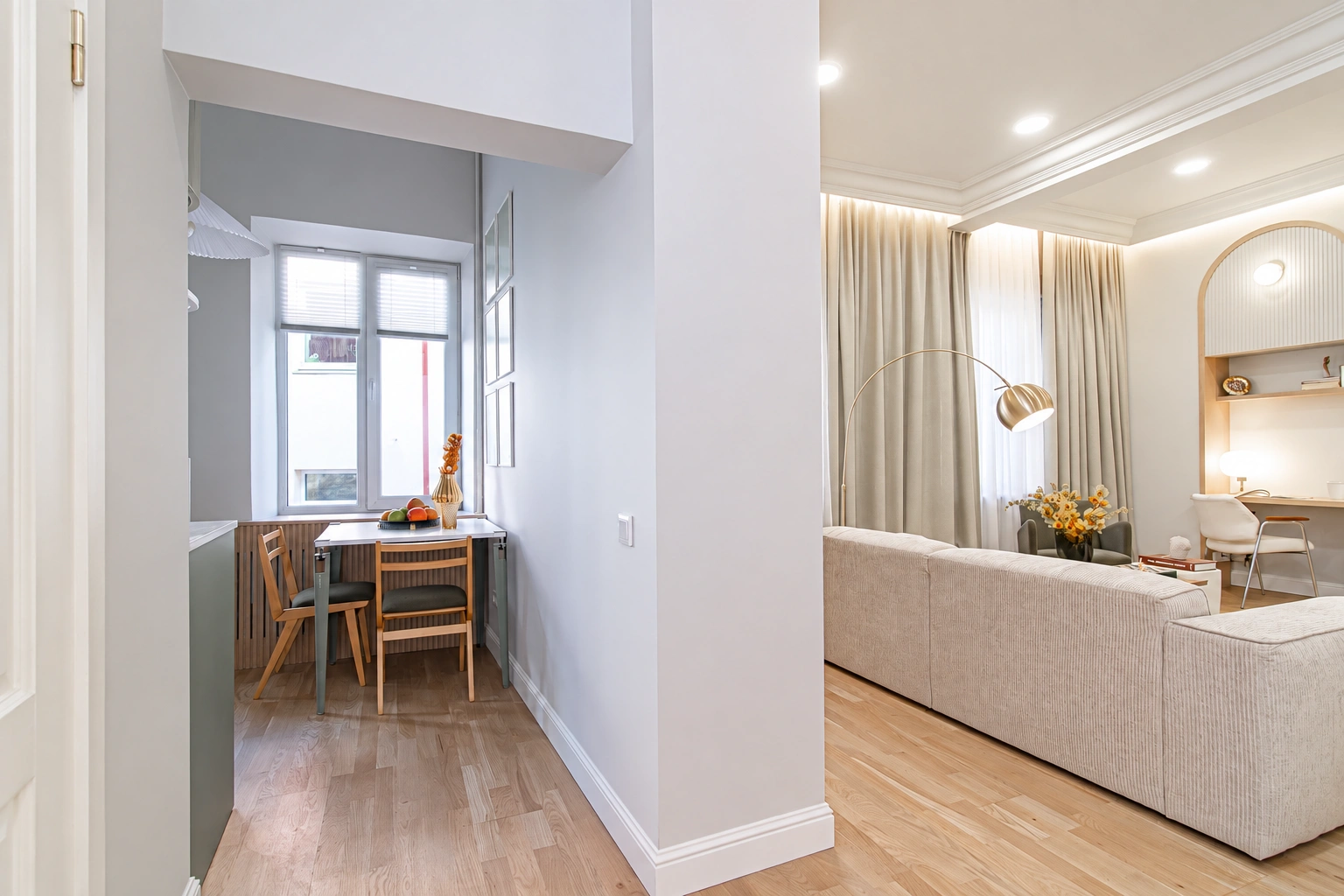 Living area with a sofa; nearby, a small table and chairs by the window.
