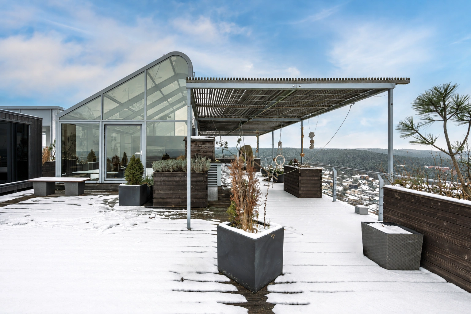Schneebedeckte Terrasse mit Pflanzentöpfen und einem Vordach.