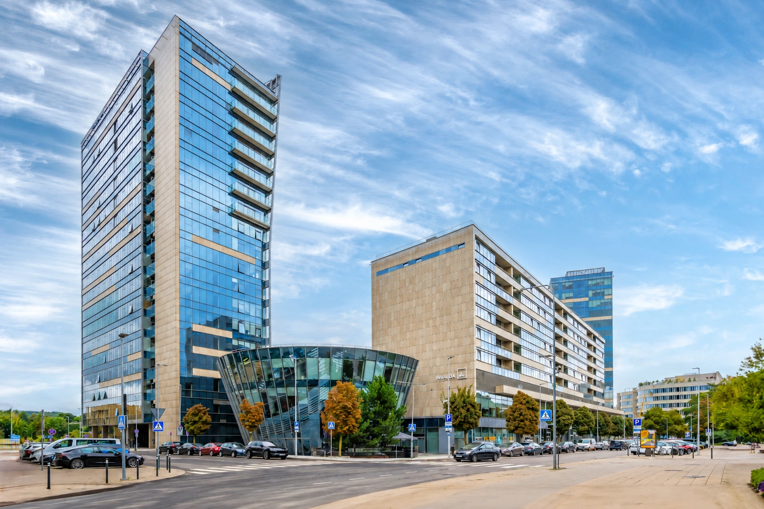 Multi-storey buildings stand by the street, and the tower on the left has a glass façade.
