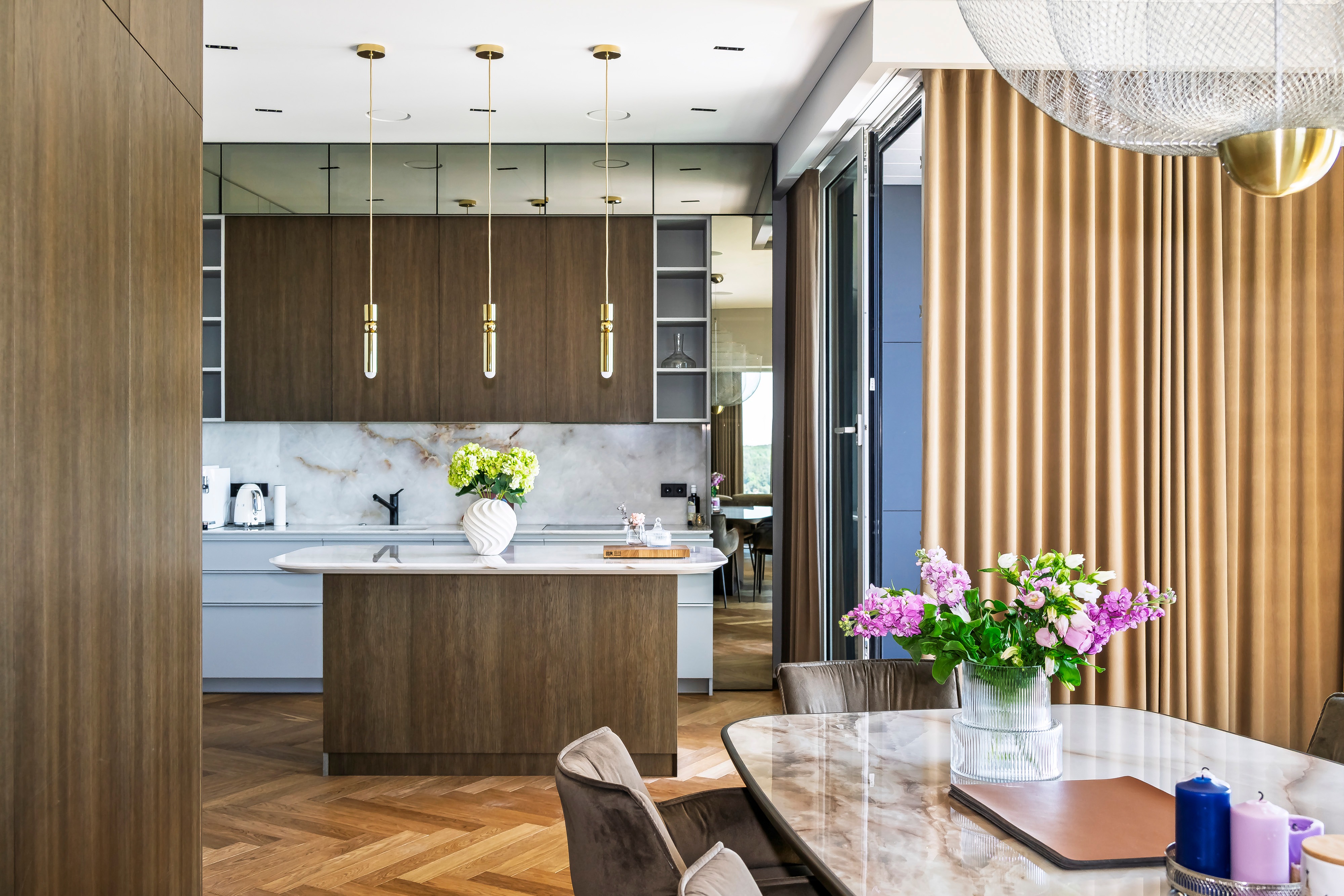 Kitchen and dining area with an island and a table with a vase of flowers on it.