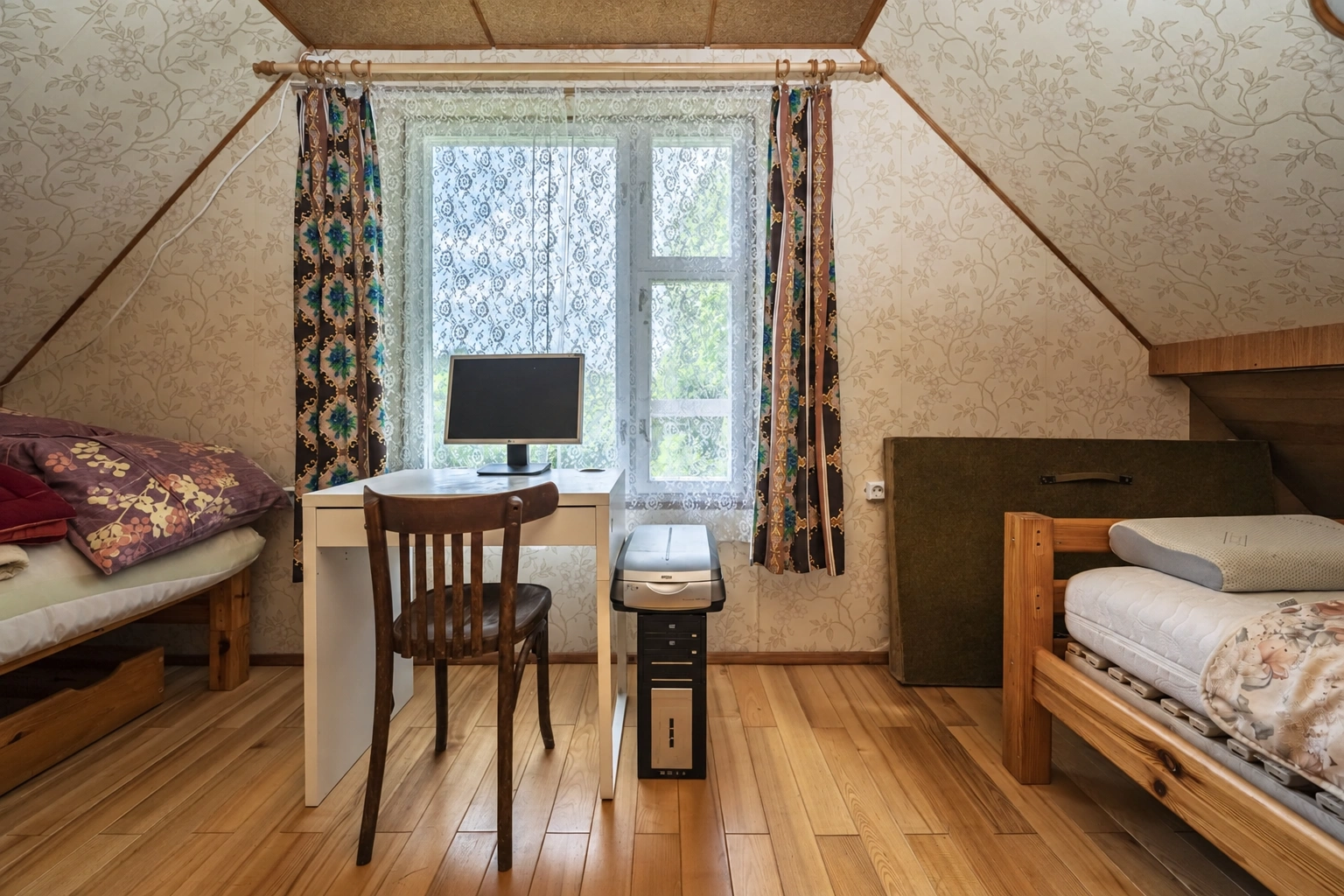Attic room with two beds and a desk by the window.