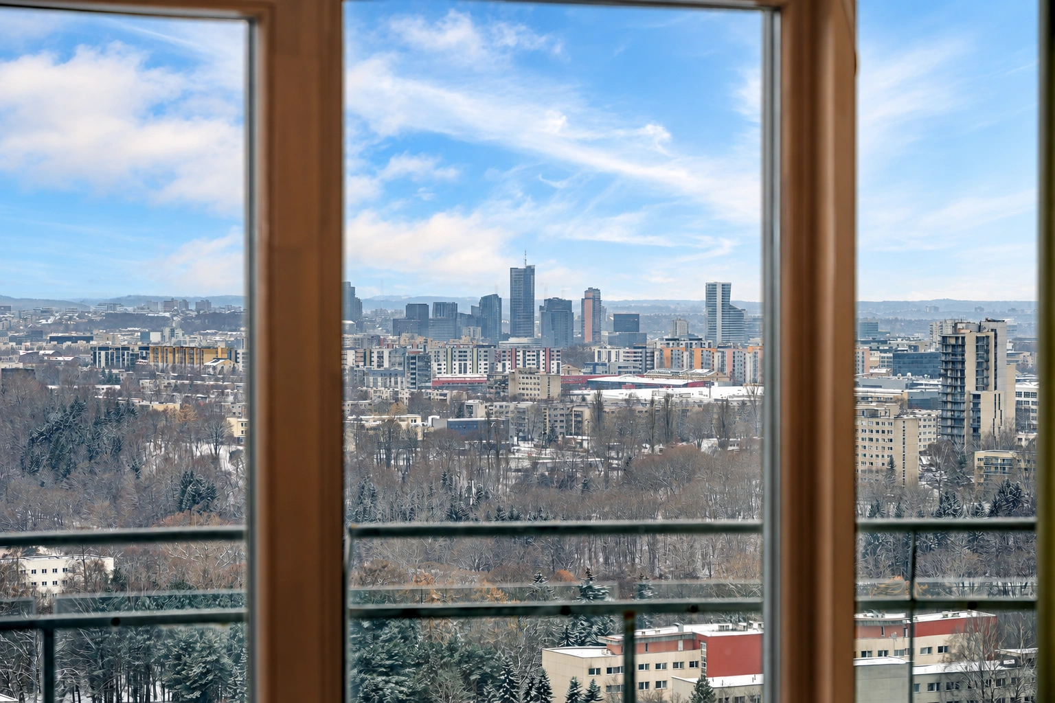 Durch die großen Fenster sind Gebäude der Stadt, Bäume und Balkongeländer zu sehen.