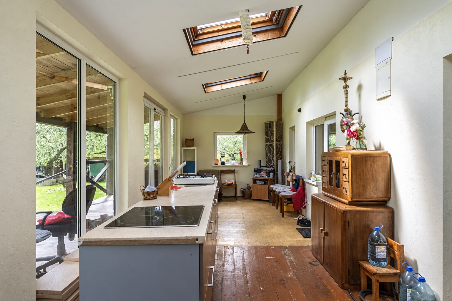 A kitchen with a long countertop along the windows and two skylights in the ceiling.