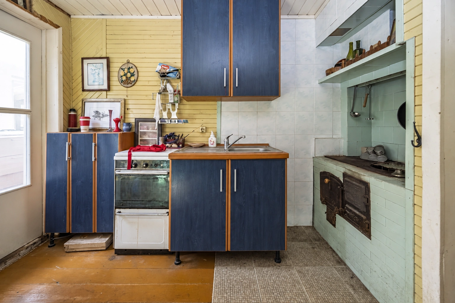 A kitchen with blue cabinets and a stove standing next to them.
